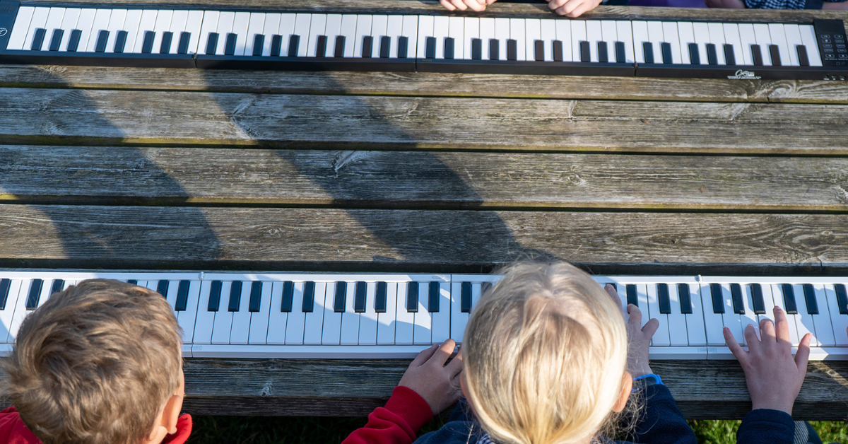 Children playing digital pianos on a table.